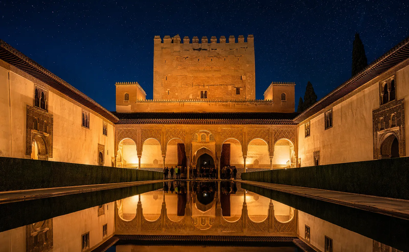 Alhambra night tour attendance revenue — illuminated Nasrid Palaces reflecting in pool, Granada Spain evening atmosphere